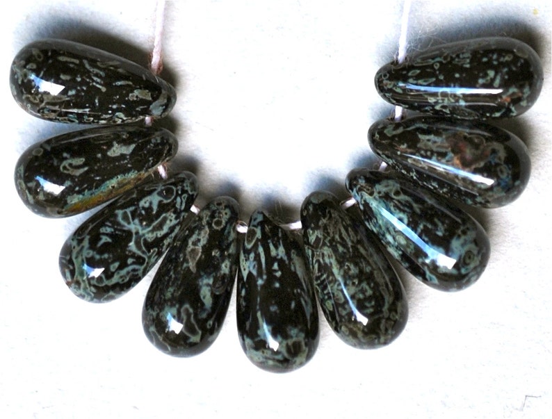 May include: A strand of ten teardrop-shaped beads with a black and green marbled pattern.
