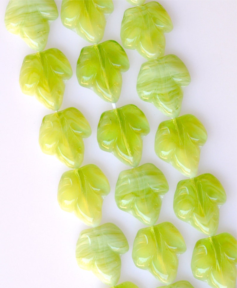 Puede incluir: Una hebra de cuentas de jade verde en forma de hoja. Las cuentas est&aacute;n talladas con un dise&ntilde;o de hoja detallado y tienen un acabado transl&uacute;cido y brillante.