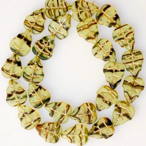 May include: A strand of green glass beads with gold leaf accents. Each bead is shaped like a leaf with a detailed vein pattern.