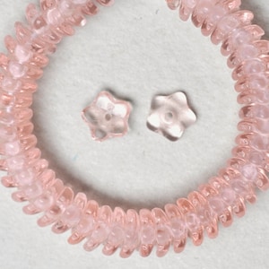 May include: A pink plastic bracelet with a flower-shaped design. Two additional flower-shaped beads are included.