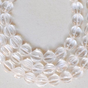 May include: A strand of clear, faceted crystal beads. The beads are round and have a ribbed texture.