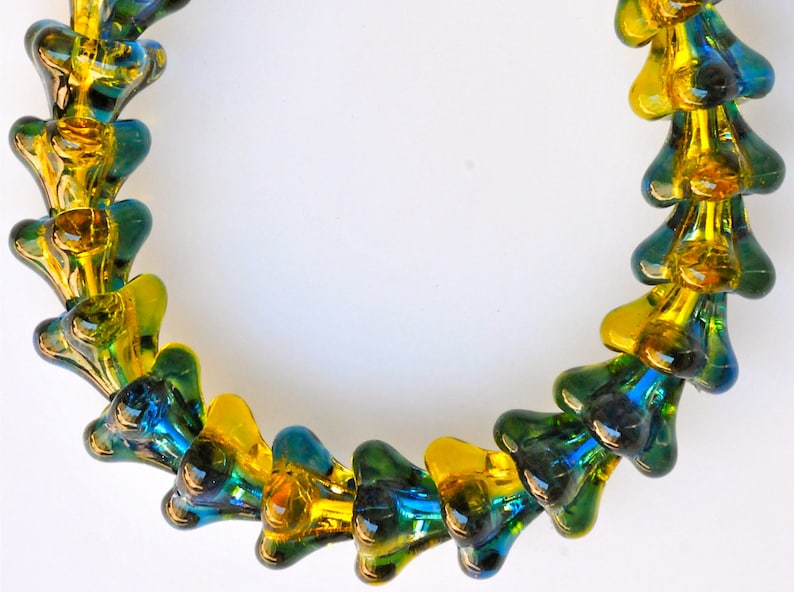 Puede incluir: Un collar hecho de cuentas de vidrio en tonos de amarillo y verde. Las cuentas tienen forma de l&aacute;grima y est&aacute;n enhebradas juntas en un patr&oacute;n repetitivo.