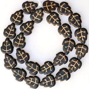 May include: A strand of black glass beads with gold leaf accents in the shape of leaves.