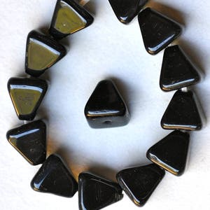 May include: A strand of black triangle-shaped glass beads. The beads are arranged in a circle with one bead in the center.