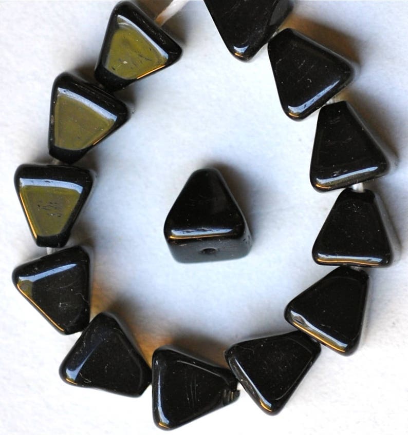 May include: A strand of black triangle-shaped glass beads. The beads are arranged in a circle with one bead in the center.