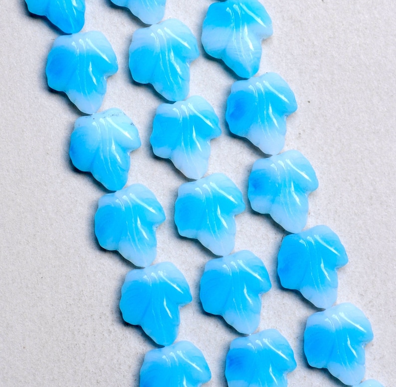 Puede incluir: Una colecci&oacute;n de hojas de vidrio azul claro con un dise&ntilde;o de remolino blanco. Las hojas est&aacute;n dispuestas en un patr&oacute;n diagonal sobre un fondo blanco.