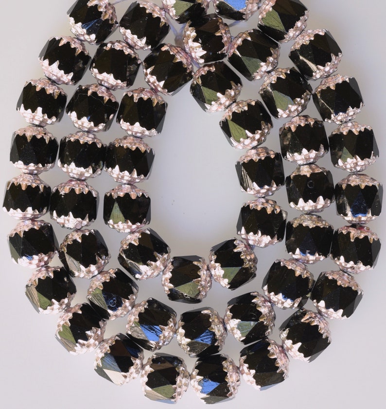K&ouml;nnte beinhalten: Eine Kette aus schwarzen facettierten Glasperlen mit silbernen Akzenten. Die Perlen sind rund und haben ein facettierten Design.