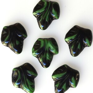 Puede incluir: Seis cuentas de vidrio en forma de hoja, negras y verdes. Las cuentas tienen un acabado brillante y son perfectas para la elaboraci&oacute;n de joyas.