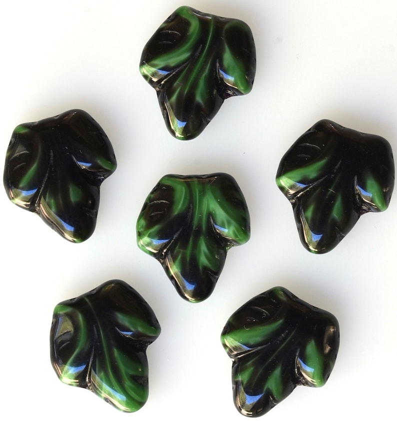 Puede incluir: Seis cuentas de vidrio en forma de hoja, negras y verdes. Las cuentas tienen un acabado brillante y son perfectas para la elaboraci&oacute;n de joyas.
