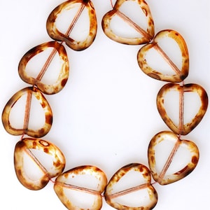 May include: A strand of brown and clear glass heart-shaped beads. The beads have a translucent appearance and are strung together on a thin thread.