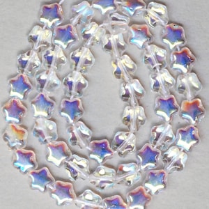 May include: A strand of iridescent clear glass star-shaped beads. The beads have a faceted design and are strung on a white thread.