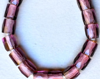 May include: A purple glass bead bracelet with faceted beads. The beads are iridescent and have a light pink hue.