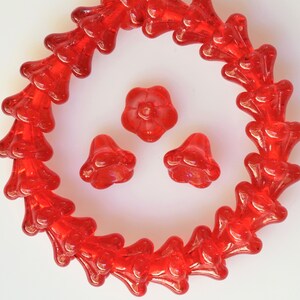 Puede incluir: Una hebra de cuentas de vidrio rojo en forma de flor, con tres cuentas de vidrio de flor roja adicionales.