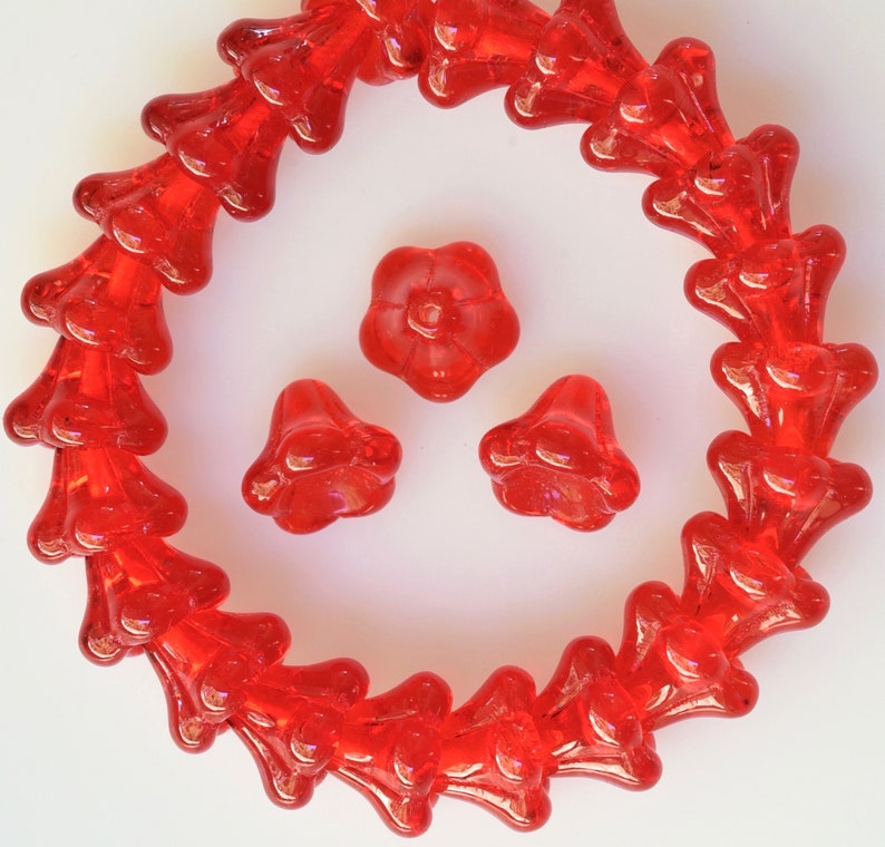 Puede incluir: Una hebra de cuentas de vidrio rojo en forma de flor, con tres cuentas de vidrio de flor roja adicionales.