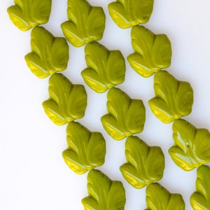 May include: A strand of green glass beads shaped like leaves. The beads are arranged in rows, with each row offset from the one above it.