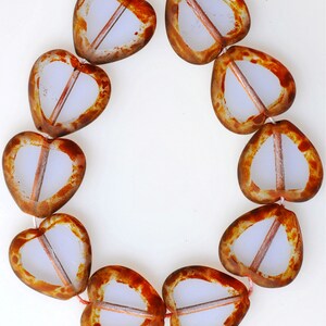 May include: A strand of heart-shaped glass beads with a brown and white mottled pattern. The beads are strung on a white cord.