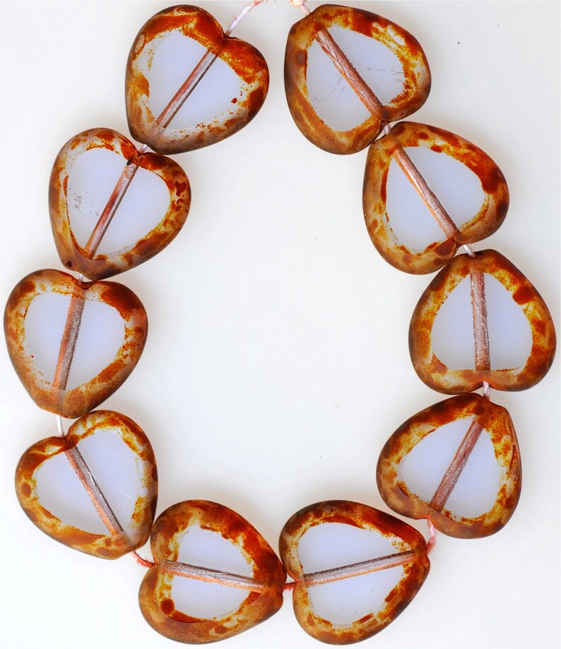 May include: A strand of heart-shaped glass beads with a brown and white mottled pattern. The beads are strung on a white cord.