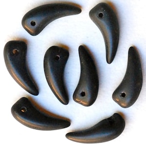 May include: Eight black, claw-shaped beads with a hole in the centre of each bead. The beads are arranged in a circle on a white background.