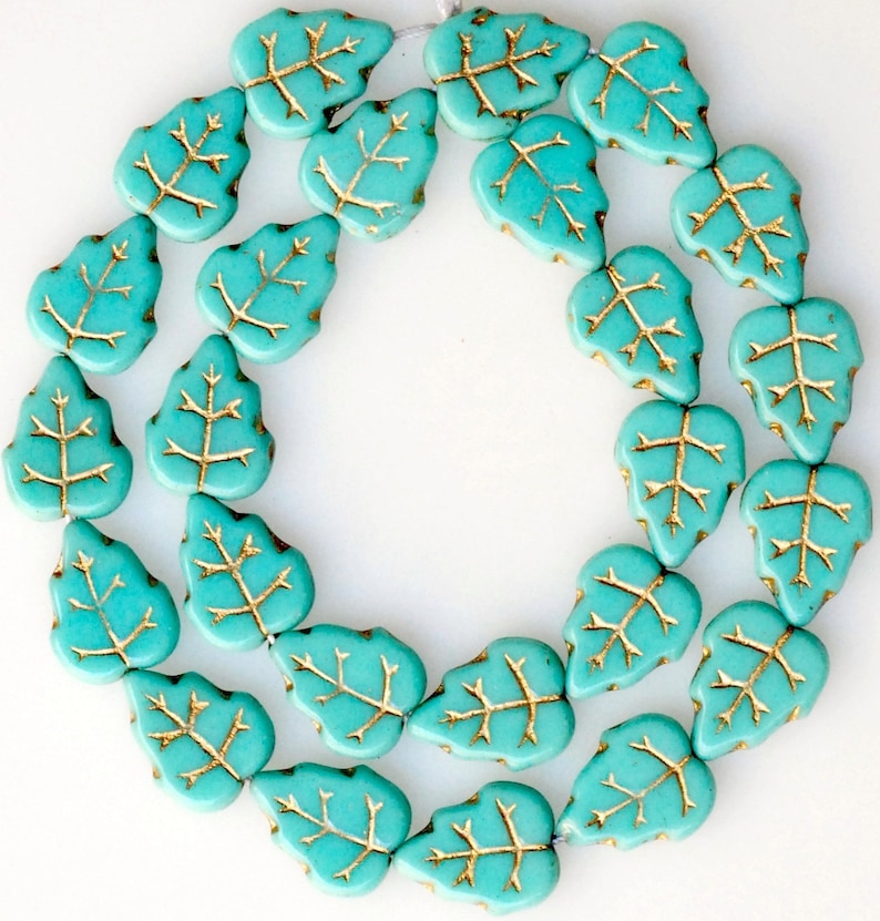 May include: A strand of turquoise blue glass beads in the shape of leaves with gold leaf accents.