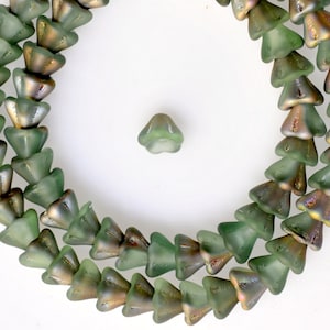 Puede incluir: Una hebra de cuentas de vidrio verde con un brillo metálico. Las cuentas tienen forma de pequeños conos puntiagudos.