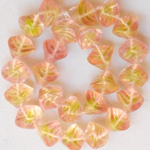 May include: A strand of pink and green glass beads with a leaf design. The beads are faceted and have a translucent appearance.