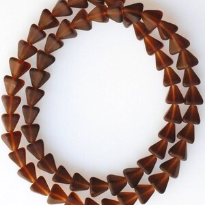 May include: A strand of brown glass triangle beads. The beads are faceted and have a glossy finish.