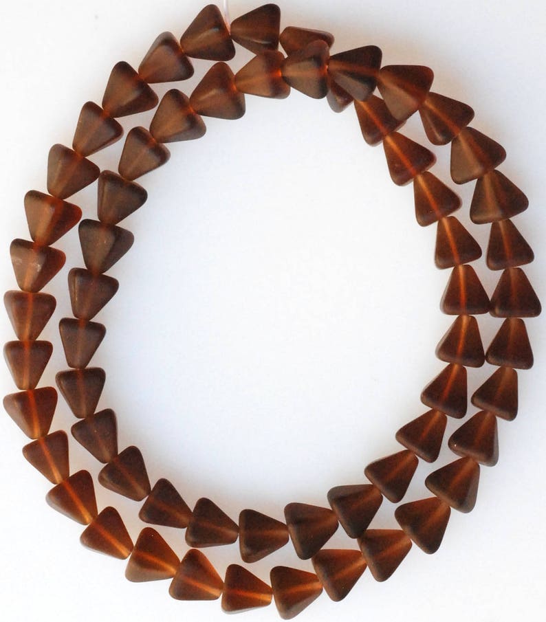 May include: A strand of brown glass triangle beads. The beads are faceted and have a glossy finish.
