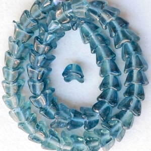 May include: A strand of light blue glass beads with a teardrop shape. The beads are strung together to form a necklace or bracelet.