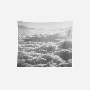 May include: A black and white photograph of a sky filled with fluffy clouds. The clouds are illuminated by the sun, creating a soft, ethereal glow.