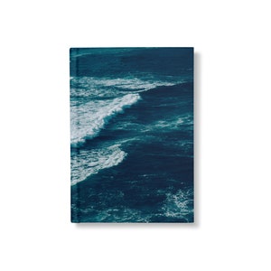 May include: A close-up photo of a deep blue ocean with white foamy waves crashing on the surface. The water is a vibrant teal color and the waves are breaking in a gentle, rolling motion.