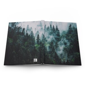 May include: A book with a photo of a misty forest on the cover. The forest is dense with tall, green trees. The photo is split across two pages.