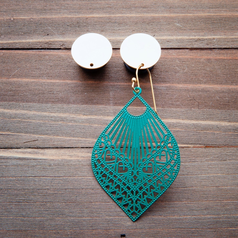 May include: Teal green filigree earring with a gold hook hanging from a white circular earring post.