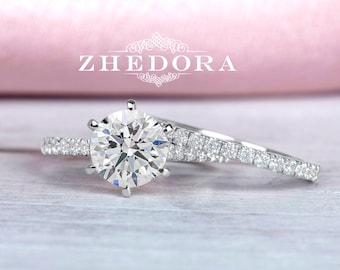 May include: A diamond engagement ring set with a large, round centre stone and a matching band with smaller diamonds. The ring is set in white gold and is on a white wooden surface.