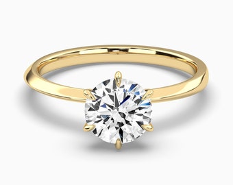 May include: A gold band engagement ring with a round, clear diamond set in a six-prong setting.