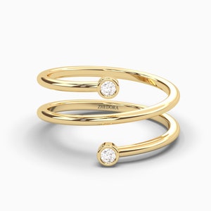 以下が含まれることがあります： バンドに小さな丸いダイヤモンドが2つセットされたゴールドのリング。リングはねじれており、バンドに「ZHEDORA」という文字が刻まれています。