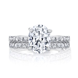 May include: A silver engagement ring set with a large oval-shaped diamond and a matching band with smaller diamonds.