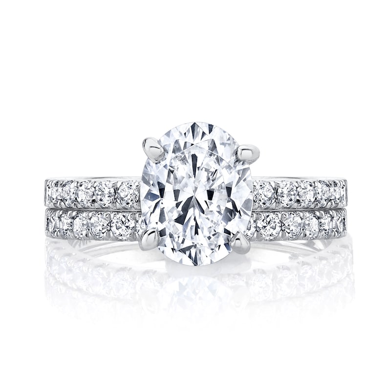 May include: A silver engagement ring set with a large oval-shaped diamond and a matching band with smaller diamonds.