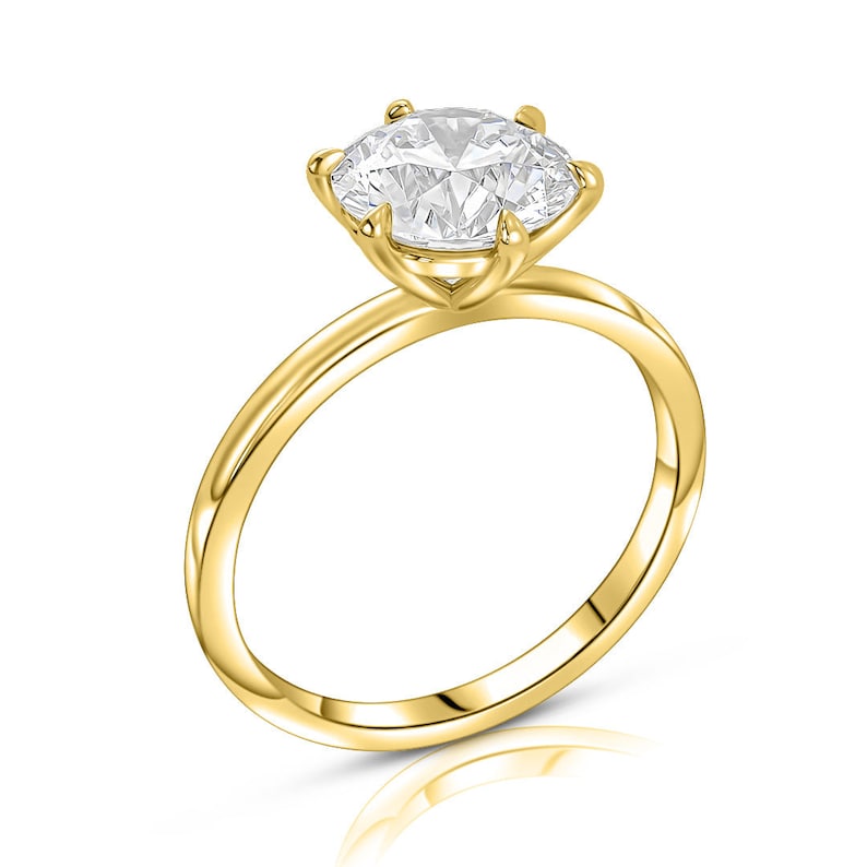 May include: A gold solitaire engagement ring with a round brilliant cut diamond.