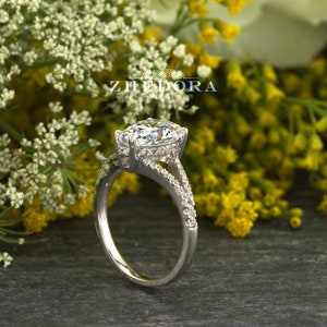 May include: A silver engagement ring with a large, clear, pear-shaped diamond. The ring has a split shank with smaller diamonds set along the band.