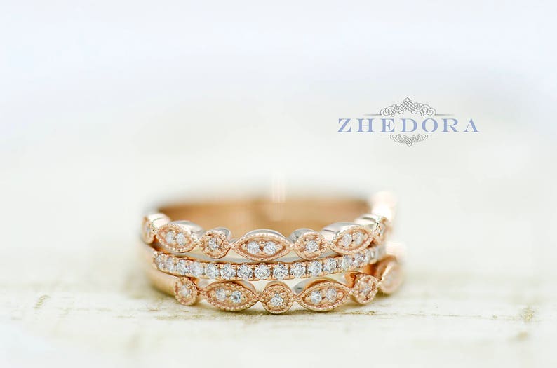 May include: Three rose gold rings with a delicate, vintage-inspired design. Each ring features a row of small, round diamonds set in a delicate, leaf-like pattern. The rings are stacked on top of each other, creating a beautiful and elegant look.