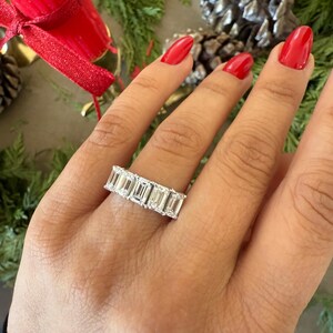 May include: A silver ring with a row of emerald-cut diamonds set in a band.