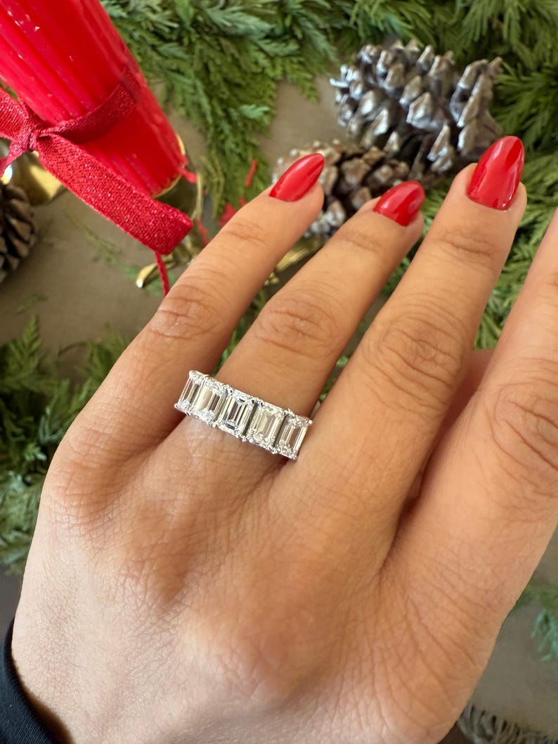 May include: A silver ring with a row of emerald-cut diamonds set in a band.