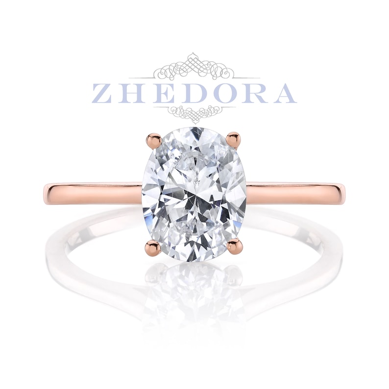 Puede incluir: Un anillo de compromiso de oro rosa con un gran diamante de forma ovalada.