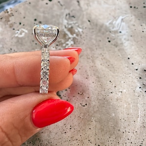 May include: A silver engagement ring with a large, round, clear diamond center stone and a pave diamond band.