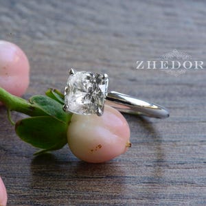 May include: A silver ring with a large, clear, cushion-cut diamond.