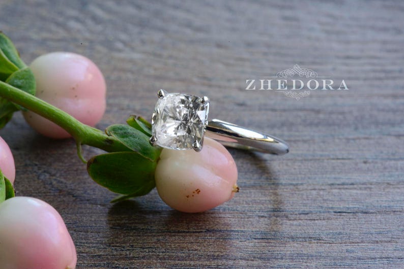 May include: A silver ring with a large, clear, cushion-cut diamond.