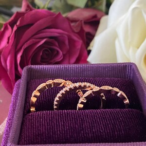 May include: Three rose gold rings with small diamonds set in a purple velvet ring box.