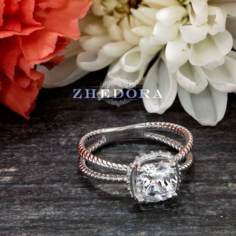 May include: A silver ring with a square-shaped diamond set in a halo setting. The ring band is twisted and has a rope-like design.