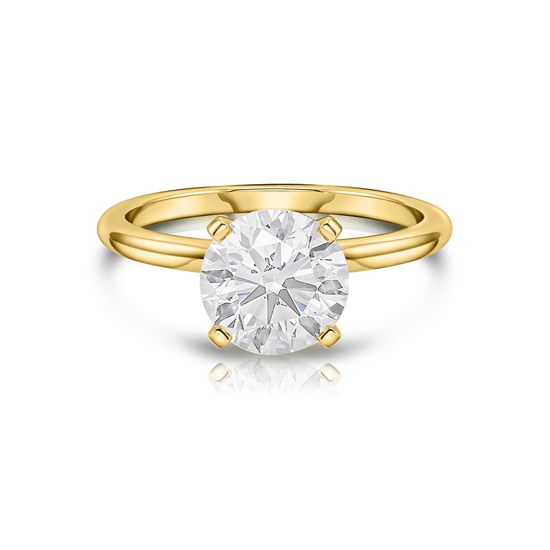 May include: A gold solitaire engagement ring with a round brilliant cut diamond.