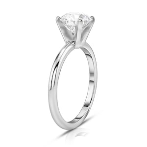 May include: A simple silver band engagement ring with a large, round, clear diamond.